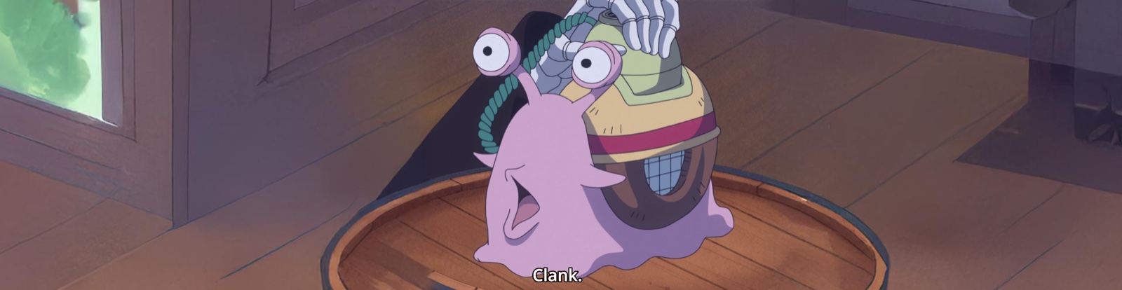 Clank — a snail-shaped intercom held in a hand, resting on a wooden barrel